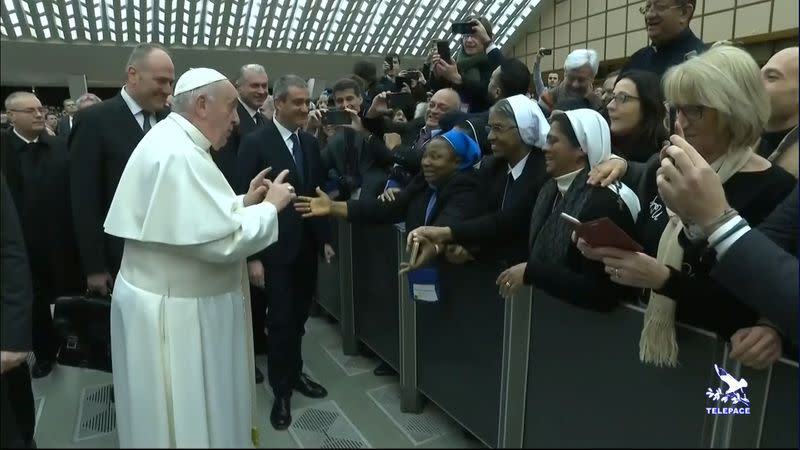 Pope Francis gestures as he jokes to a nun "You bite! I will give you a kiss but you stay calm. Don't bite!", as he arrives for the general audience at the Vatican