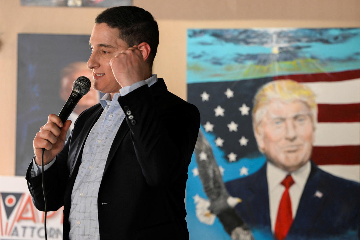 Republican senate candidate Josh Mandel, with a painting of Trump behind him, speaks at a campaign event.