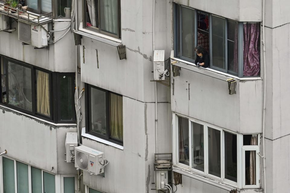 A woman looks out the window of a residential building during a Covid-19 coronavirus lockdown in the Jing'an district in Shanghai on April 23, 2022.