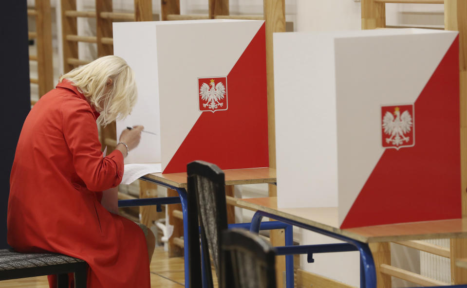 A woman votes by ballot in an election to the Polish parliament in Warsaw, Poland, on Oct. 13, 2019. Poles are voting Sunday in a parliamentary election, that the ruling party of Jaroslaw Kaczynski is favored to win easily, buoyed by the popularity of its social conservatism and generous social spending policies that have reduced poverty. (AP Photo/Czarek Sokolowski)