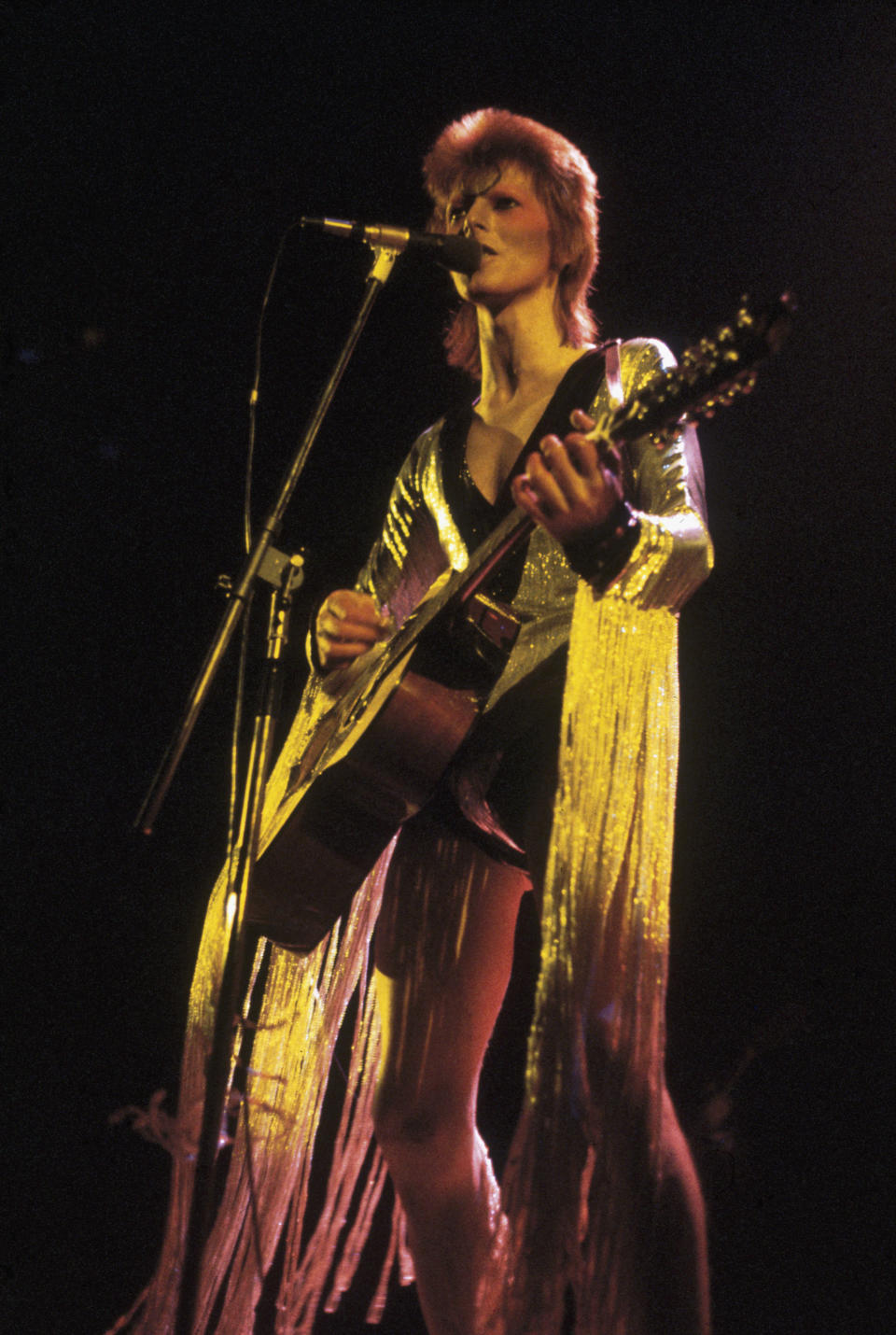 David Bowie performing as Ziggy Stardust at the Hammersmith Odeon, 1973. He is wearing a silver costume with gold tassels by Japanese designer Kansai Yamamoto. (Photo by Debi Doss/Hulton Archive/Getty Images)   