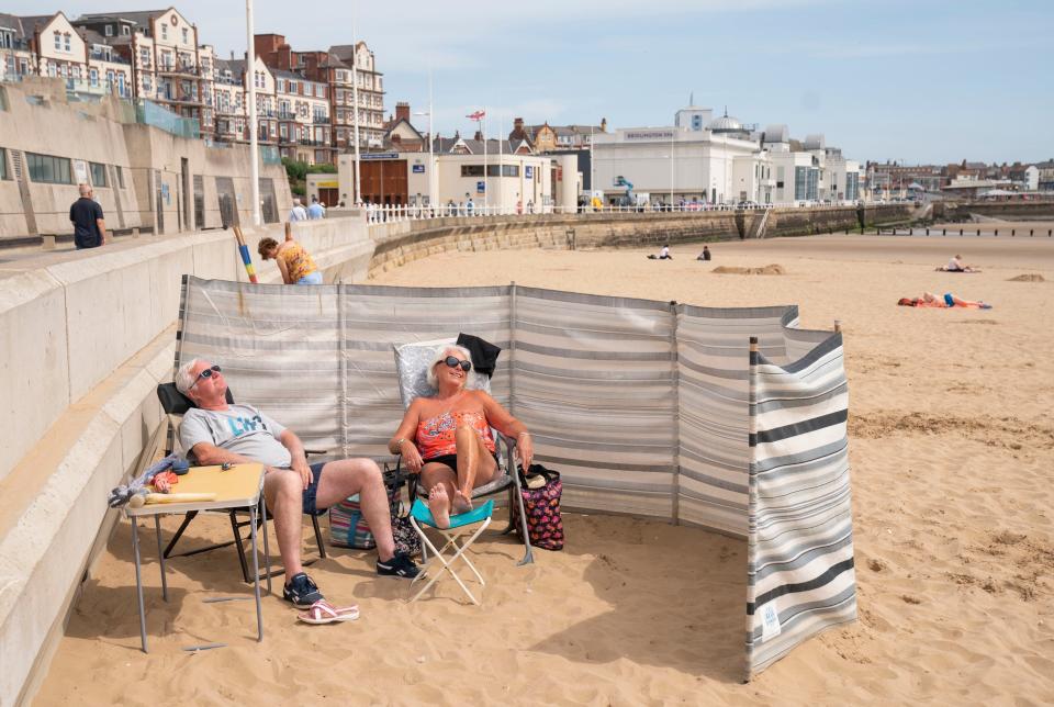 People sunbathe as they enjoy the hot weather on Bridlington beach in Yorkshire (PA)