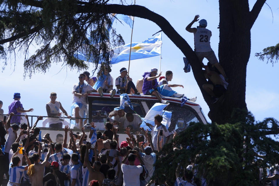 Soccer fans wave at players on an open-top bus carrying the Argentine national soccer team that won the World Cup title in Buenos Aires, Argentina, Tuesday, Dec. 20, 2022. (AP Photo/Natacha Pisarenko)