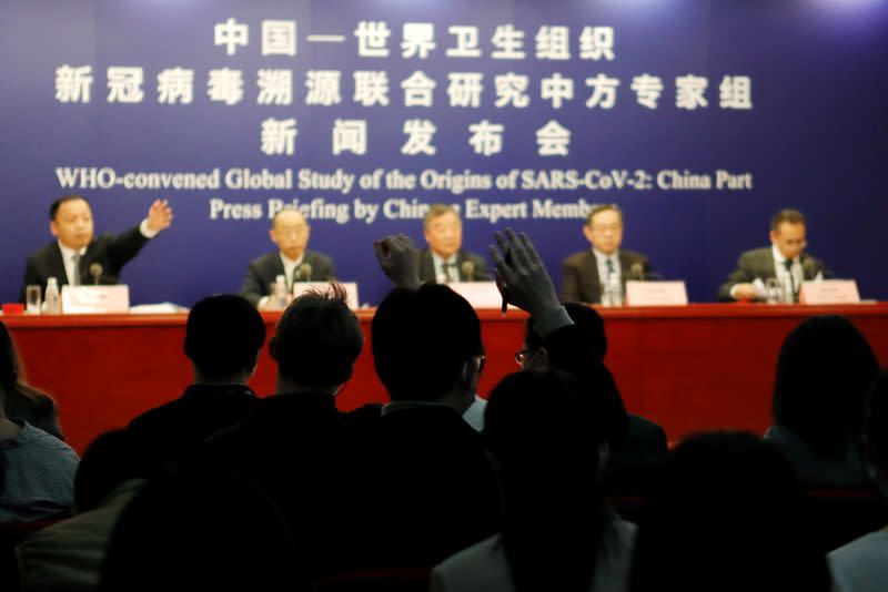 Journalists raise hands at a news conference on the WHO-China joint study, in Beijing