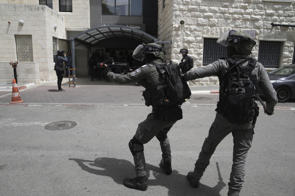 An Israeli border police officer in riot gear takes aim with riot control rounds outside of the hospital where the body of slain Al Jazeera veteran journalist Shireen Abu Akleh will be taken from to to her final resting place, in east Jerusalem, Friday, May 13, 2022. Abu Akleh, a Palestinian-American reporter who covered the Mideast conflict for more than 25 years, was shot dead Wednesday during an Israeli military raid in the West Bank town of Jenin. (AP Photo/Mahmoud Illean)