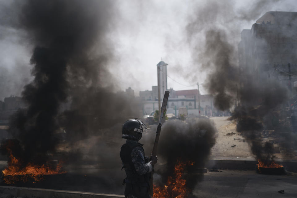 A riot police officer stands next to tires set on fire during a protest at a neighborhood in Dakar, Senegal, Friday, June 2, 2023. Clashes between police and supporters of Senegalese opposition leader Ousmane Sonko left nine people dead, the government said Friday, with authorities issuing a blanket ban on the use of several social media platforms in the aftermath of the violence (AP Photo/Leo Correa)