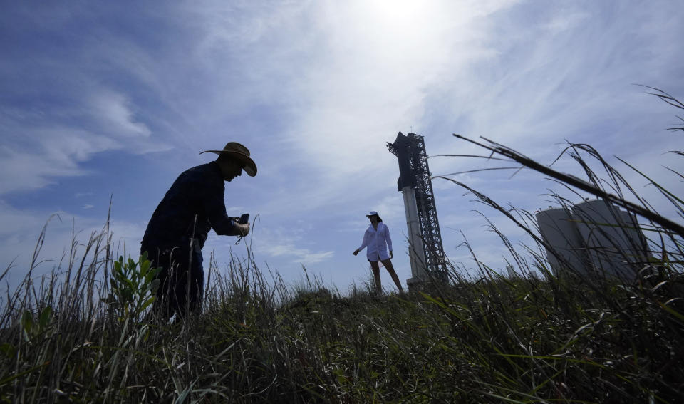 A couple take photos at the site where SpaceX's Starship, the world's biggest and most powerful rocket, sits ready for launch in Boca Chica, Texas, Sunday, April 16, 2023. The test launch is scheduled for Monday. (AP Photo/Eric Gay)