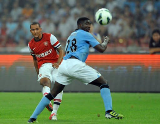 Theo Walcott of Arsenal kicks the ball pass Kolo Toure (R) of Manchester City during a friendly match in Beijing. Manchester City beat Arsenal 2-0