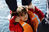 Greek Coast Guard officers move a girl from a dinghy carrying refugees and migrants aboard the Ayios Efstratios Coast Guard vessel, during a rescue operation at open sea between the Turkish coast and the Greek island of Lesbos, February 8, 2016. REUTERS/Giorgos Moutafis