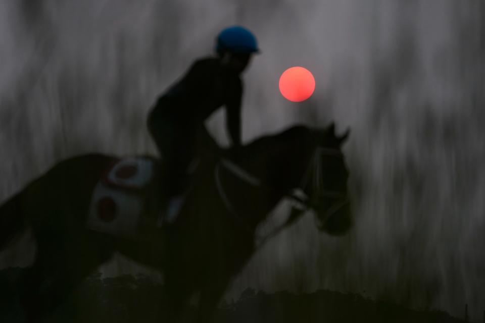 Haze from northern wildfires obscures the rising sun as horses train ahead of the Belmont Stakes horse race, Wednesday, June 7, 2023, at Belmont Park in Elmont, N.Y.