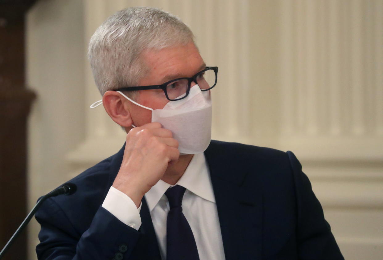 Apple Inc CEO Tim Cook leans on his hand while listening to President Biden 