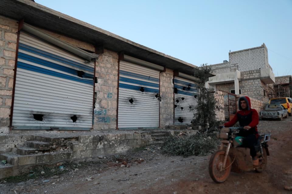 A Syrian man rides his motorcycle along damaged shops after an operation by the U.S. military in the Syrian village of Atmeh in Idlib province, Syria, Thursday, Feb. 3, 2022 (AP)