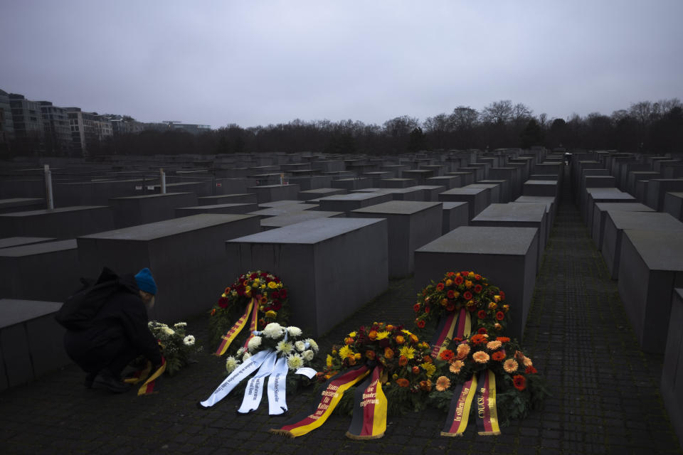 A woman adjusts a wreath placed at the Memorial to the Murdered Jews of Europe on the International Holocaust Remembrance Day in Berlin, Germany, Friday, Jan. 27, 2023. (AP Photo/Markus Schreiber)