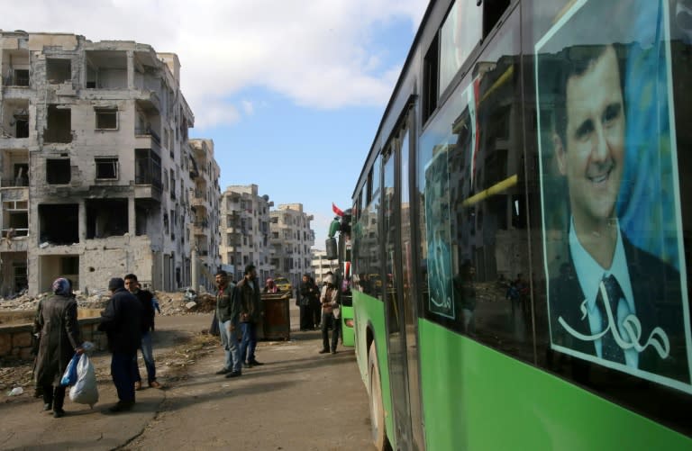 Syrians, from various western districts, wait at a bus stop in Aleppo's central Jamiliyeh neighbourhood before taking part in a bus trip through government-held territory of the divided city