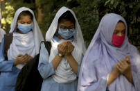 Students wearing face masks to prevent the spread of the coronavirus as they pray upon their arrival at their school, in Karachi, Pakistan, Monday, Jan. 18, 2021. Pakistani authorities started to reopen schools in phases despite a steady increase in deaths and infections from the coronavirus, official said. (AP Photo/Fareed Khan)