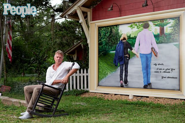 <p>Daymon Gardner</p> John Schneider in front of the mural of him and Alicia on his Louisiana property