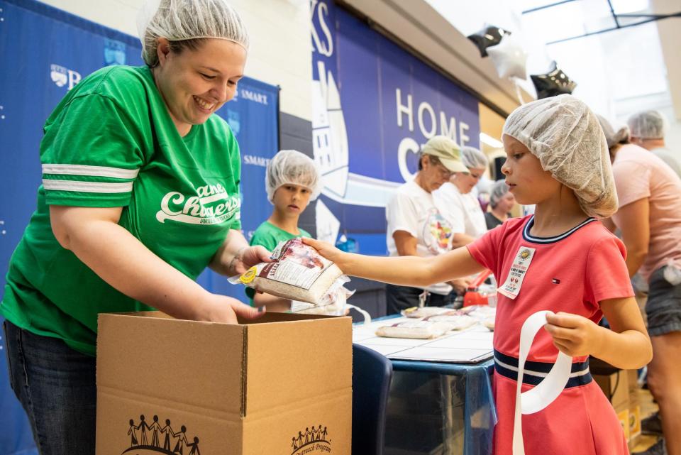 File - Faith Parkinson, left, director of finance at the United Way of Bucks County, and Charlotte Strouse, 7, of Middletown, stickers and packs meals with her brother, Walter Strouse, 8, during the 2019 Bucks Knocks Out Hunger event. The popular food-packing event returns June 17.