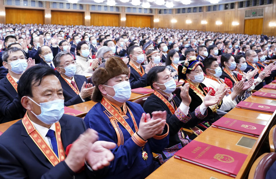 In this photo released by China's Xinhua News Agency, attendees applaud during a ceremony to mark the official end of extreme poverty in China held at the Great Hall of the People in Beijing, Thursday, Feb. 25, 2021. The ruling Communist Party is celebrating the official end of extreme poverty in China with a propaganda campaign that praises President Xi Jinping's role, adding to efforts to cement his image as a history-making leader who is reclaiming his country's rightful place as a global power. (Yan Yan/Xinhua via AP)