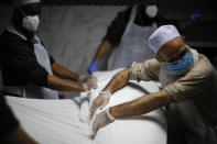 The body of Mohammad Altaf, who died at 48 of COVID-19, is ritually washed and wrapped before being given funeral prayers at Al-Rayaan Muslim Funeral Services, Sunday, May 17, 2020, in the Brooklyn borough of New York. (AP Photo/John Minchillo)