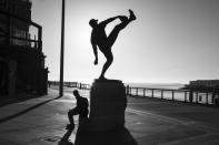 A man sits beneath a statue of San Francisco Giants Hall of Fame pitcher Juan Marichal outside Oracle Park and looks out to McCovey Cove in San Francisco on April 24, 2020. Normally, the months leading into summer bring bustling crowds to the city's famous landmarks, but this year, because of the coronavirus threat they sit empty and quiet. Some parts are like eerie ghost towns or stark scenes from a science fiction movie. (AP Photo/Eric Risberg)