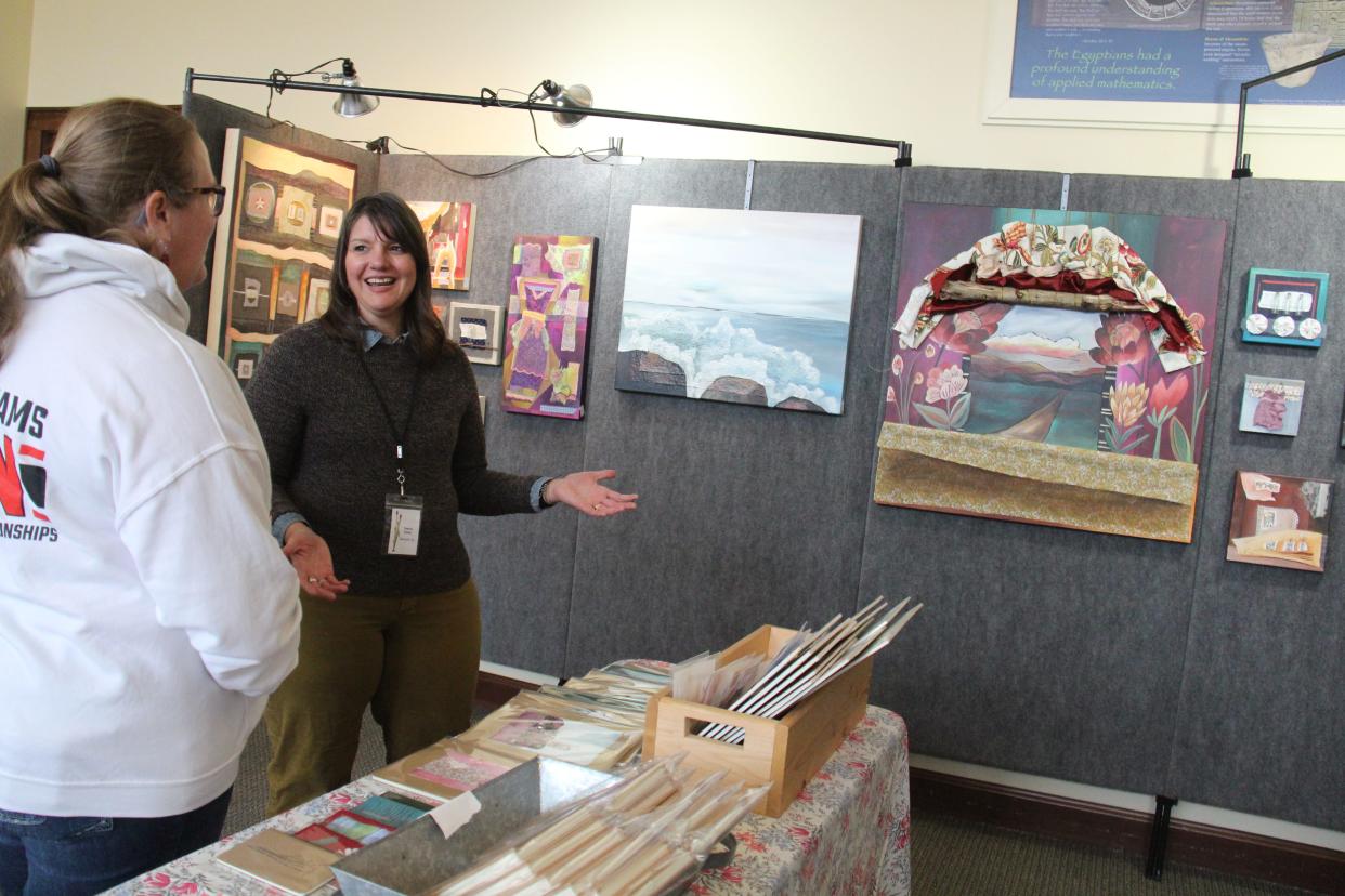 Artist Teena Case chats with Lynn Royer, of Minburn, at her booth inside the Town/Craft Building during the Art on the Prairie festival on Saturday, Nov. 12, 2022, in Perry.