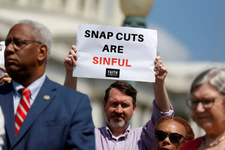 FILE PHOTO: A man holds up a sign protesting against cuts to the Supplemental Nutrition Assistance Program (SNAP) during a press conference on Capitol Hill in Washington, U.S., May 7, 2018. REUTERS/Joshua Roberts/Files