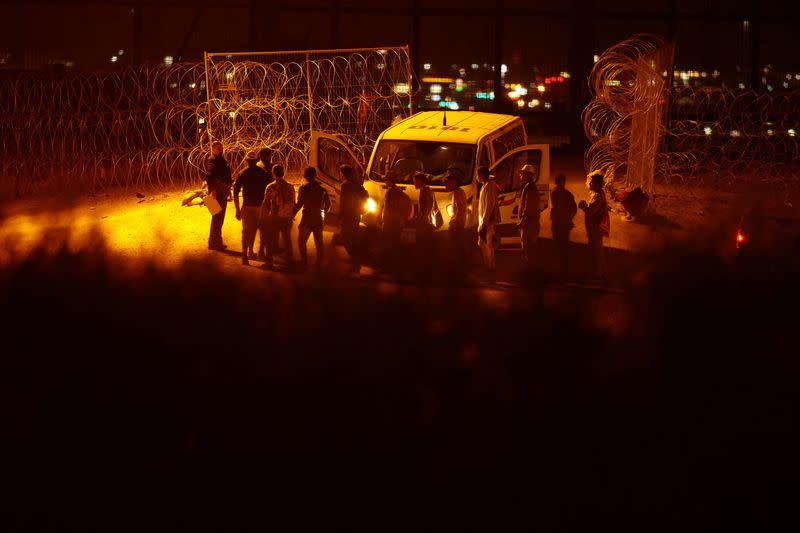 FILE PHOTO: Migrants seeking asylum in the United States gather near a border wall on the banks of the Rio Bravo River, as seen from Ciudad Juarez