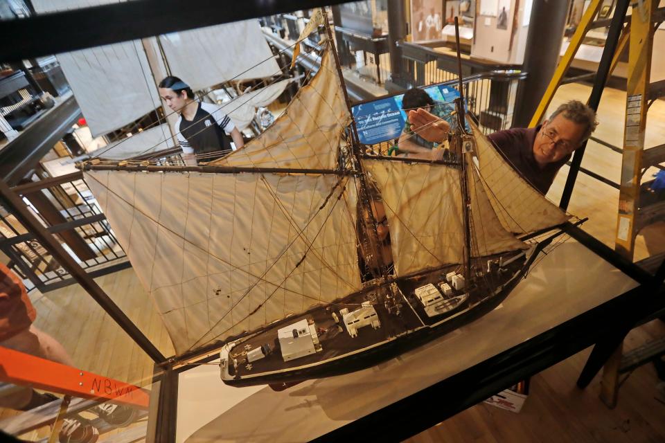 Scott Benson, right, takes a closer look at the alignment of the model of the schooner Ernestina made by Julio Gomes using popsicle sticks, after it is placed inside the cabinet he made for it  on the second floor of the Lagoda room inside the Whaling Museum