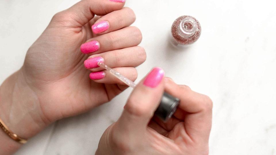 painting manicured nail with pink and glitter