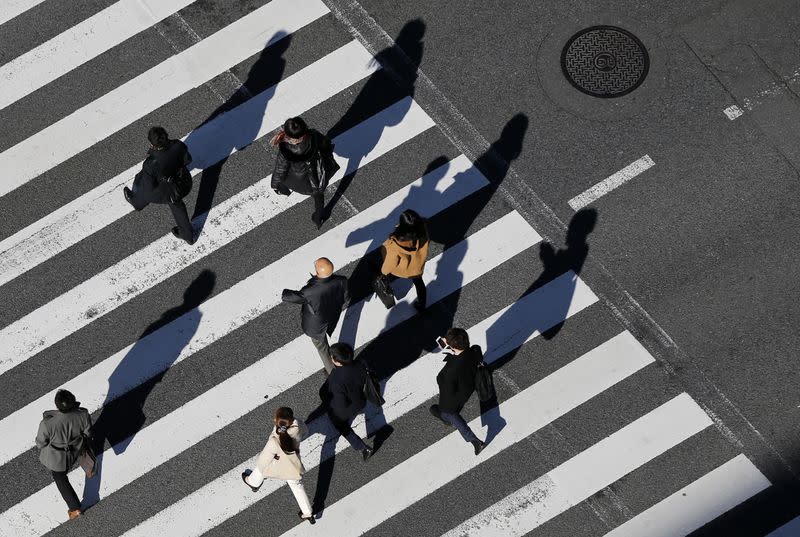 Pedestrians cast shadows on the crosswalk near the headquarters of the Bank of Japan in Tokyo