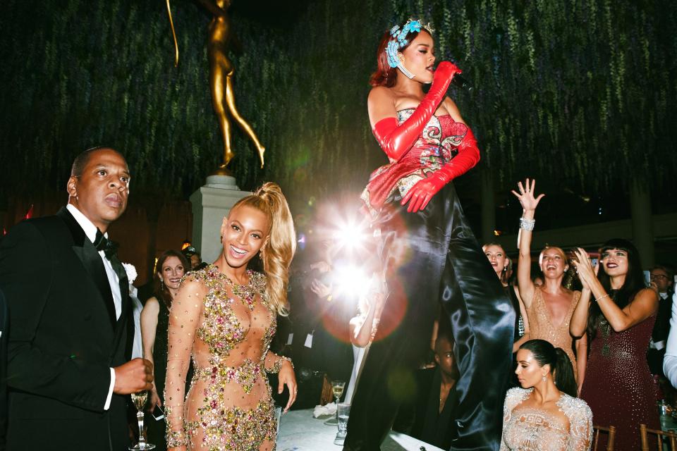 Atop a reinforced table, Rihanna serenades a crowd that includes Beyoncé, Jay-Z, and Kim Kardashian West.