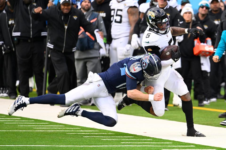 Jacksonville Jaguars safety Andre Cisco (5) is knocked out of bound by Tennessee Titans quarterback Ryan Tannehill (17) after an interception during the second half of an NFL football game Sunday, Jan. 7, 2024, in Nashville, Tenn. (AP Photo/John Amis)