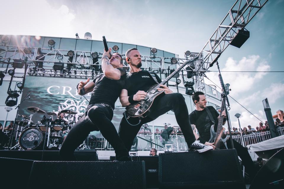 Creed performing on the stage of a ship, with the Miami skyline behind them.