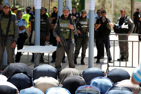 FILE PHOTO: Palestinians pray in front of Israeli policemen and newly installed metal detectors at an entrance to the compound known to Muslims as Noble Sanctuary and to Jews as Temple Mount in Jerusalem's Old City July 16, 2017. REUTERS/Ronen Zvulun/File Photo