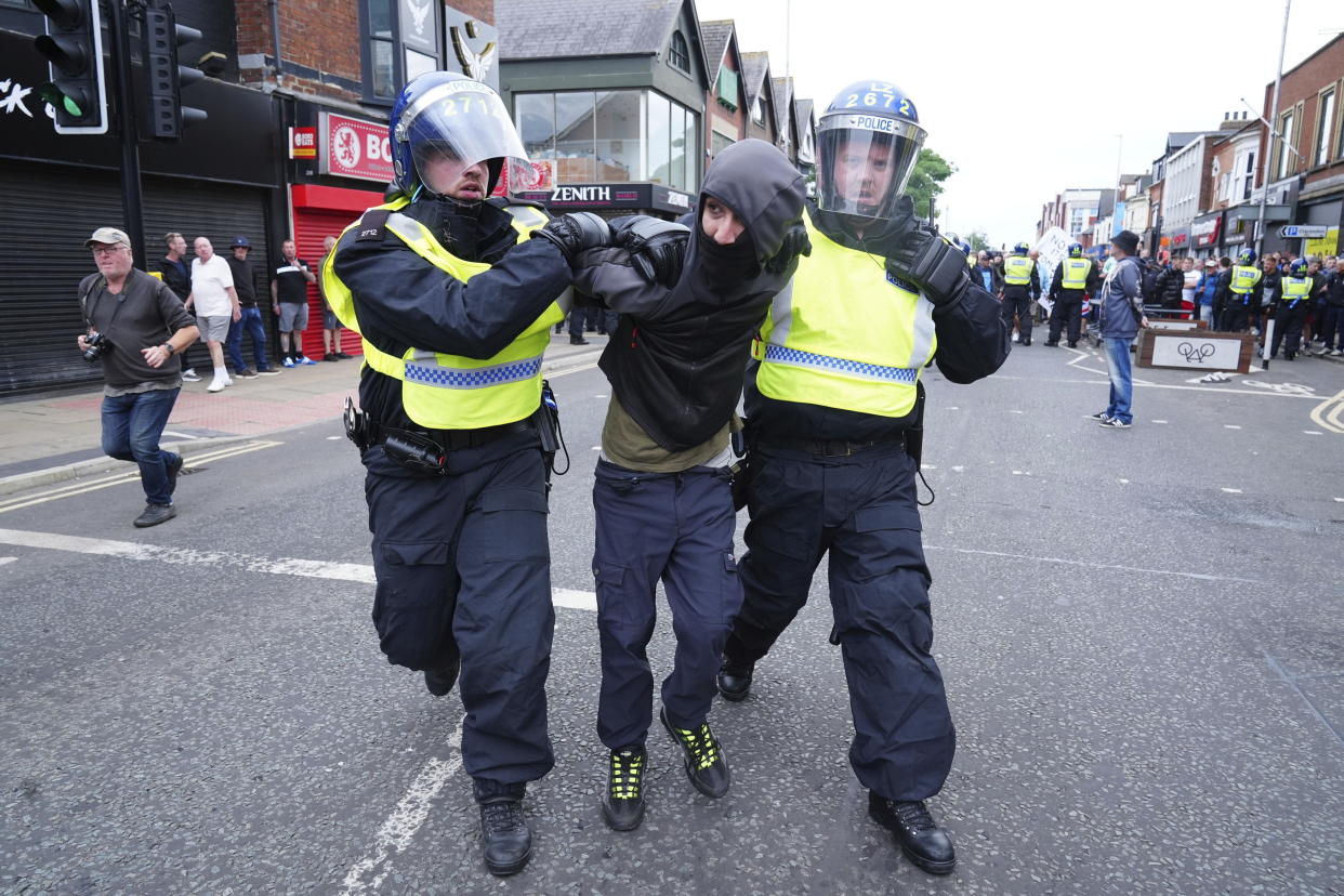 A man is detained by police officers in Middlesbrough, England