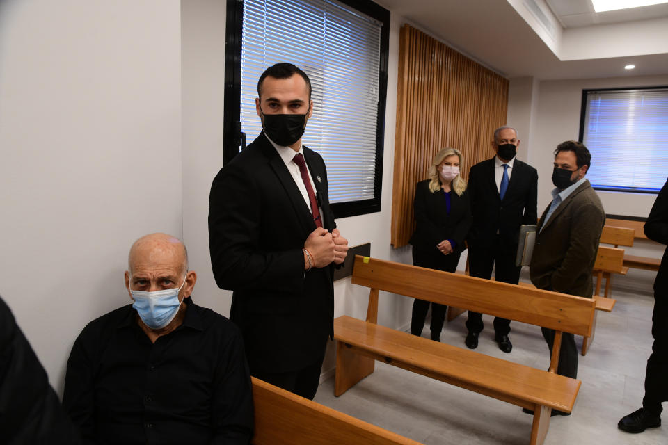 Former Israeli Prime Minister Ehud Olmert, left, and former Israeli Prime Minister Benjamin Netanyahu, second right and his wife Sarah, sit in the Tel Aviv Magistrate's Court, Monday, Jan. 10, 2022, during a preliminary hearing in a defamation lawsuit. Former Prime Minister Benjamin Netanyahu, his wife and son appeared in the Tel Aviv Magistrate’s court Monday for the opening of their case against Olmert, Netanyahu’s predecessor as Israel’s prime minister. The Netanyahus are suing Olmert for saying they suffered from “mental illness” during an interview last year. (Avshalom Sassoni/Pool Photo via AP)