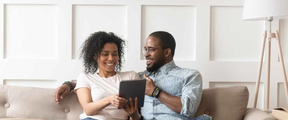 Happy african couple husband and wife shopping online for a mortgage