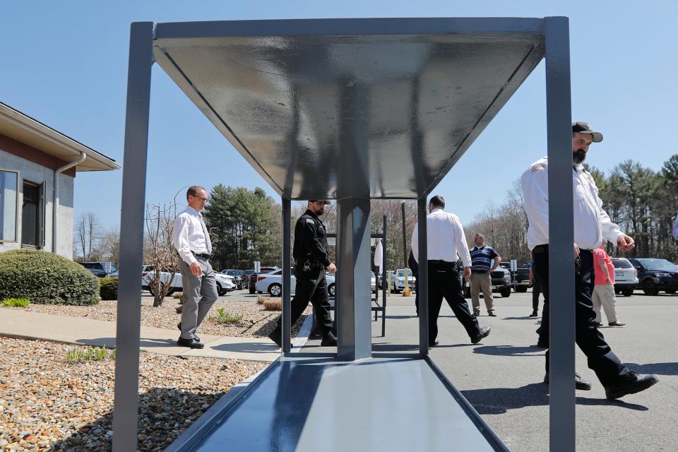 Correction officers walk past the prototype anti-suicide bed which features no points to wrap sheets around during a press conference by Bristoll County Sheriff Paul Heroux.