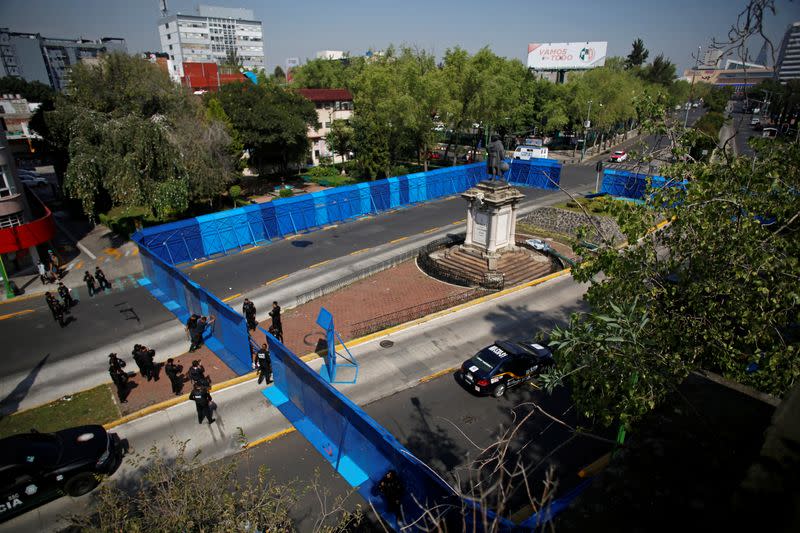 Police officers stand guard in front of metal fencing surrounding the statue of Italian explorer Cristobal Colon, also known as Christopher Columbus, in Mexico City