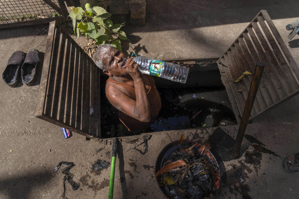 FILE - A man drinks water as he takes a break from cleaning an underground sewage on a hot summer day in Mumbai, India, May 2, 2024. Sizzling heat across Asia and the Middle East in late April that echoed last year’s destructive swelter was made 45 times more likely in some parts of the continent because of human-caused climate change, a study found. (AP Photo/Rafiq Maqbool, File)