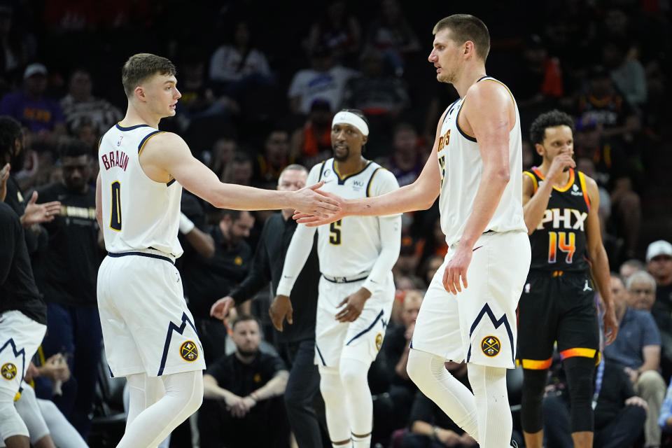 Denver Nuggets center Nikola Jokic, right, greets guard Christian Braun leaves the game during the second half of Game 6 of an NBA basketball Western Conference semifinal game against the Phoenix Suns, Thursday, May 11, 2023, in Phoenix. The Nuggets eliminated the Sun in their 125-100 win. (AP Photo/Matt York)