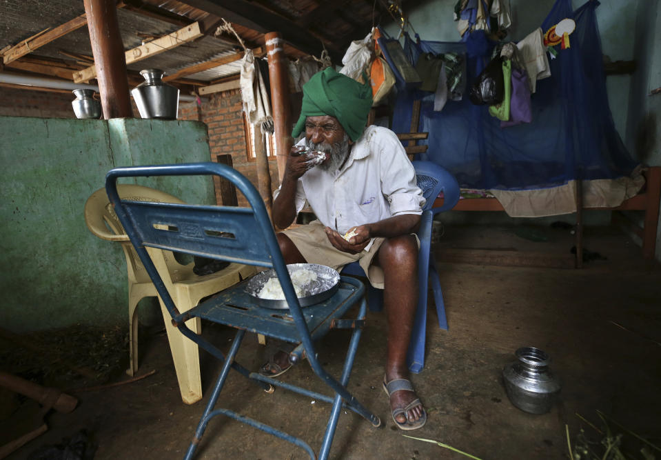 Kalmane Kamegowda, a 72-year-old shepherd, eats his lunch at home after visiting the hillock where he has created 16 ponds, in Dasanadoddi village, 120 kilometers (75 miles) west of Bengaluru, India, Wednesday, Nov. 25, 2020. Kamegowda, who never attended school, says he's spent at least $14,000 from his and his son’s earnings, mainly through selling sheep he tended over the years, to dig a chain of 16 ponds on the picturesque hill near his village. (AP Photo/Aijaz Rahi)