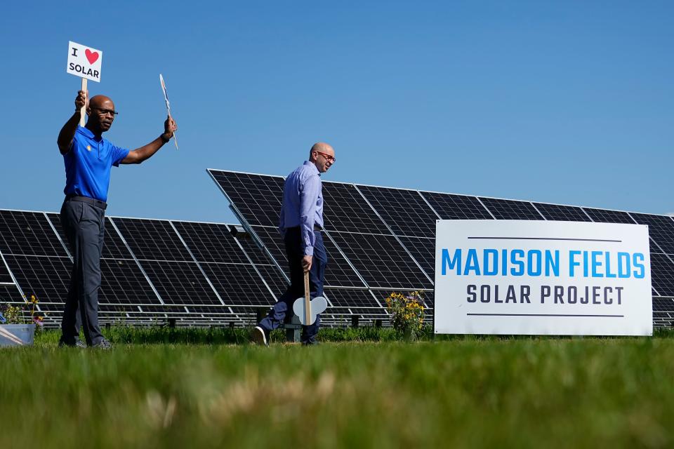 Jul 11, 2024; Mechanicsburg, OH, USA; Glenn Wright, senior vice president of Shell Energy Americas, holds a “I (heart) solar” sign alongside JC Sandberg, chief advocacy officer at the American Clean Power Association during the opening ceremony for the Madison Fields Solar Farm.