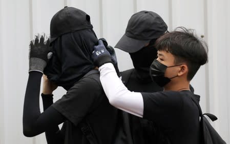 FILE PHOTO: Anti-government protesters adjust their masks during a protest at Wong Tai Sin district, in Hong Kong