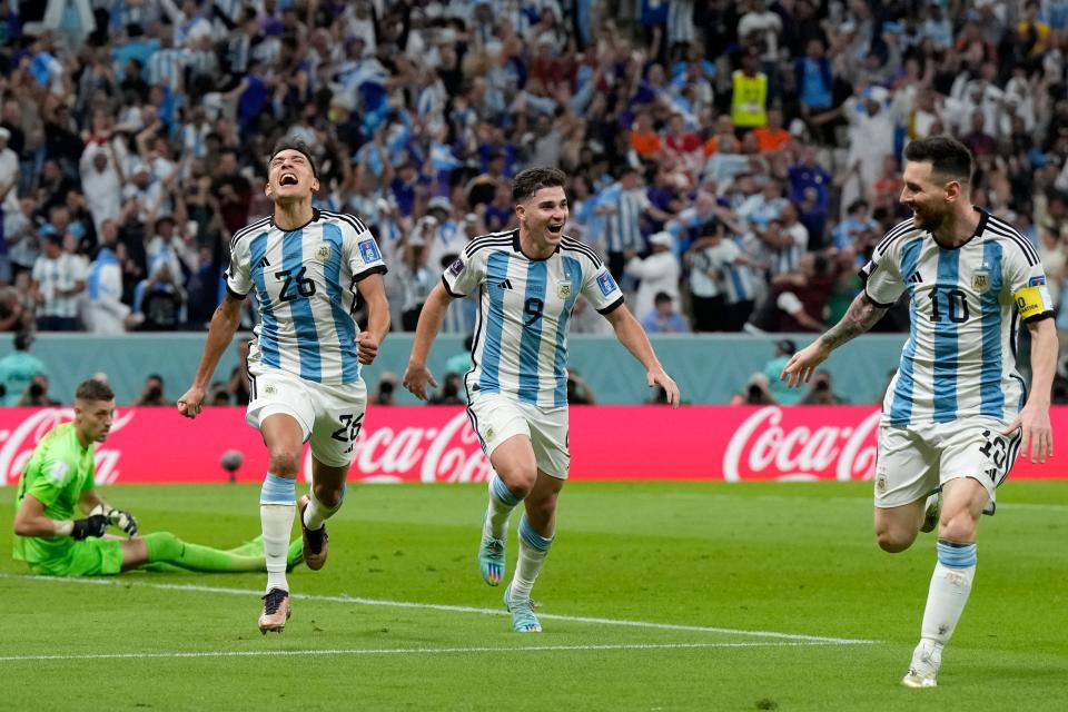 Argentina's Nahuel Molina, left, celebrates with Julian Alvarez, center, and Lionel Messi, right, after scoring the opening goal during the World Cup quarterfinal soccer match between the Netherlands and Argentina, at the Lusail Stadium in Lusail, Qatar, Friday, Dec. 9, 2022. (AP Photo/Ricardo Mazalan)