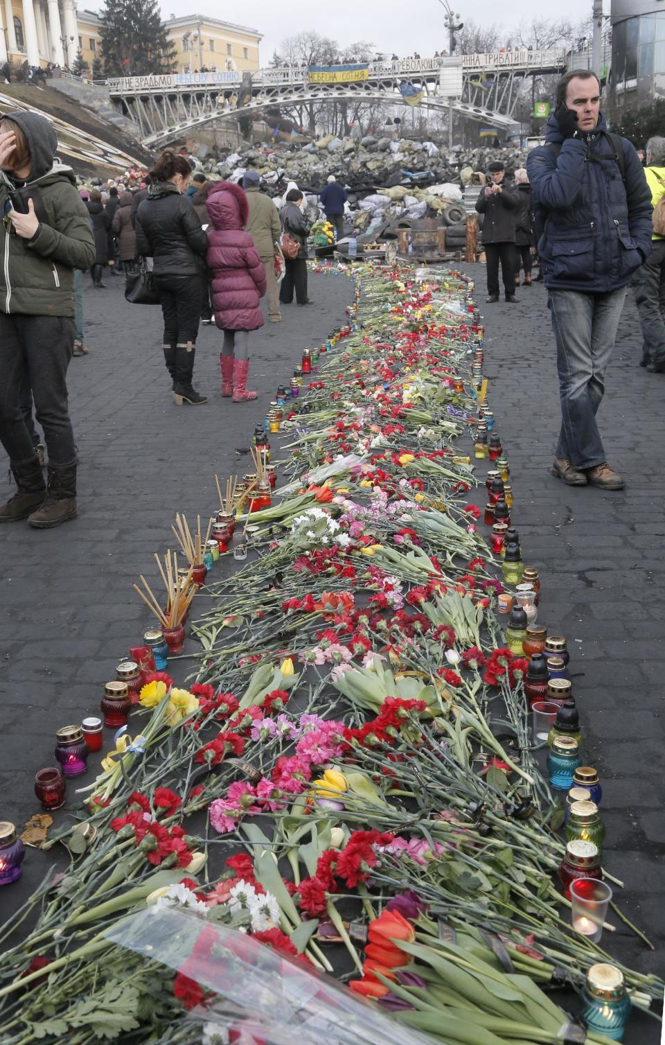 People lay down flowers on one of the streets leading to Independence Square, Kiev, the epicenter of the country's recent unrest, on a mourning day, Monday, Feb. 24, 2014. Ukraine’s acting government issued a warrant Monday for the arrest of President Viktor Yanukovych, last reportedly seen in the pro-Russian Black Sea peninsula of Crimea, accusing him of mass crimes against protesters who stood up for months against his rule. (AP Photo/Efrem Lukatsky)