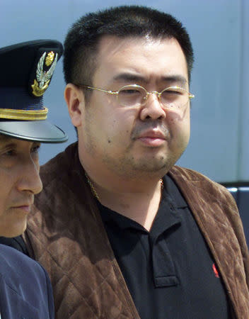 FILE PHOTO: A man (R) believed to be North Korean heir-apparent Kim Jong-nam is escorted by police as he boards a plane upon his deportation from Japan at Tokyo's Narita international airport May 4, 2001. REUTERS/Eriko Sugita/File Photo