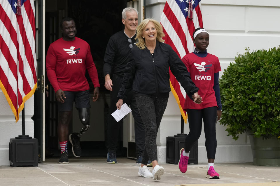 First lady Jill Biden holding hands with Gabrielle Reynolds, right, daughter of Will B. Reynolds III, U.S. Army veteran and founding board member of Team RWB , left, and Veterans Affairs Secretary Denis McDonough, arrive for the Joining Forces Military Kids Workout on the South Lawn of the White House in Washington, Saturday, April 29, 2023. The event is in honor of the Month of the Military Child. (AP Photo/Carolyn Kaster)