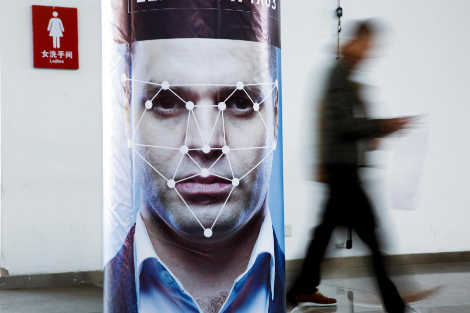 A man walks past a poster simulating facial recognition software in Beijing, China (REUTERS/Thomas Peter)