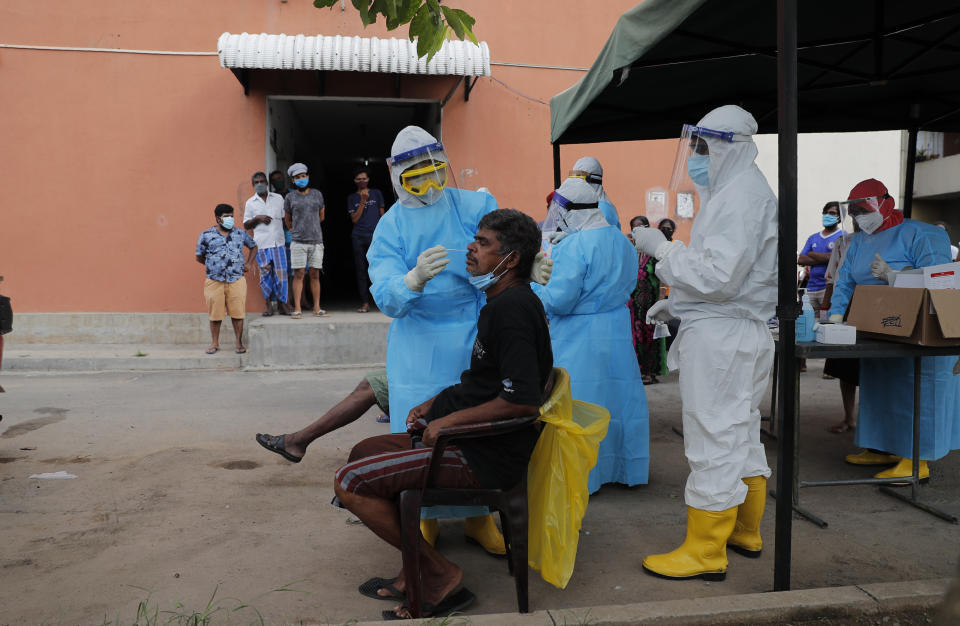 A Sri Lankan health official takes swab samples from a man to test for COVID-19 in Colombo, Sri Lanka, Monday, Nov. 23, 2020. (AP Photo/Eranga Jayawardena)